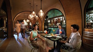 A restaurant with a high arched ceiling, hanging pendant lights, and a bar area with bottles and glasses. - Resorts World Genting - Genting Grand (Genting Highlands)