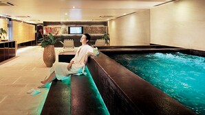 A person relaxing by a pool with a television in the background. - Resorts World Genting - Genting Grand (Genting Highlands)