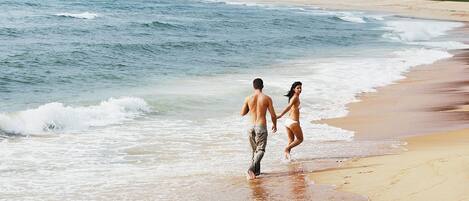 Escena de playa con una pareja caminando por la orilla.