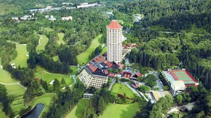 Vista aerea di un campo da golf con un grande albergo, un campo da tennis e vegetazione circostante.