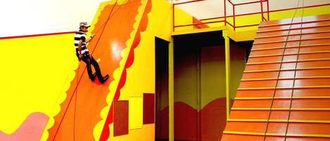 A brightly colored indoor play area with a slide and a climbing structure.