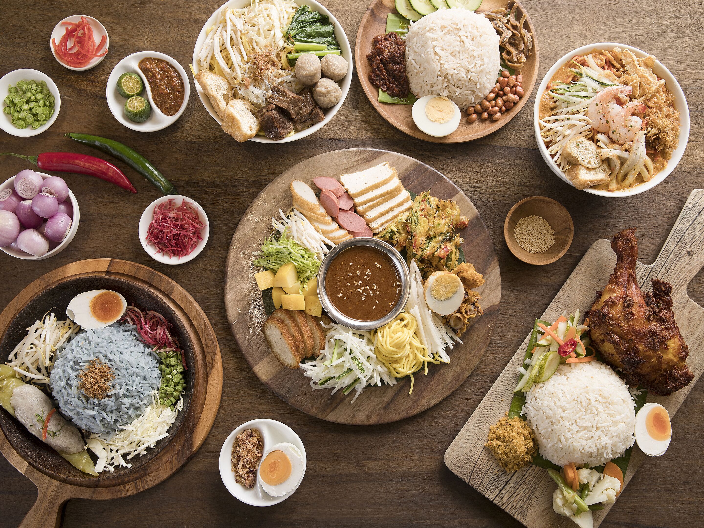A variety of dishes including rice, vegetables, and meat, arranged on wooden plates.