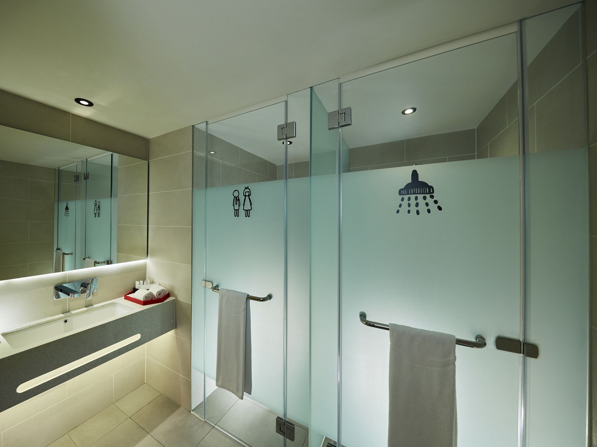Un bany modern amb dutxa de vidre, un lavabo amb mirall i un escurapulides.