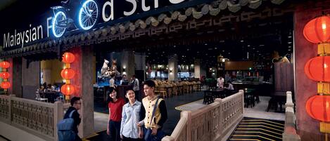 A restaurant named 'Malaysian Food Street' with a traditional Asian architectural style, featuring a sign with a bicycle and a neon light.