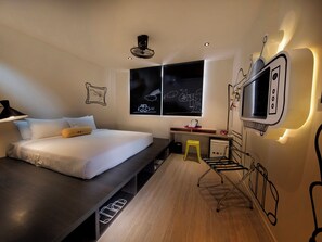 Une chambre à coucher moderne, équipée d’un lit, d’un bureau et d’une télévision.