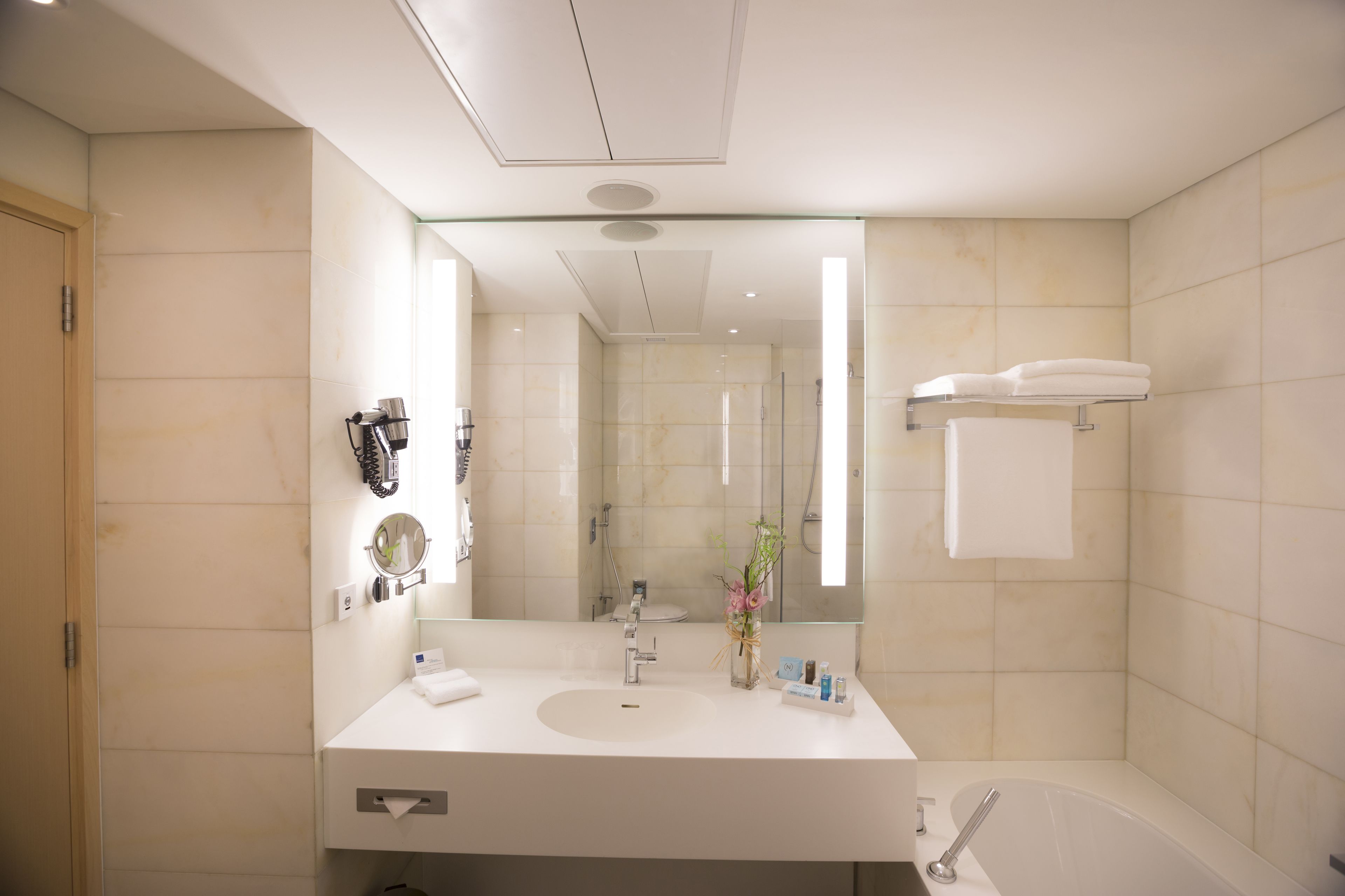 A modern bathroom with a large mirror, a sink, a shower, and a bathtub.