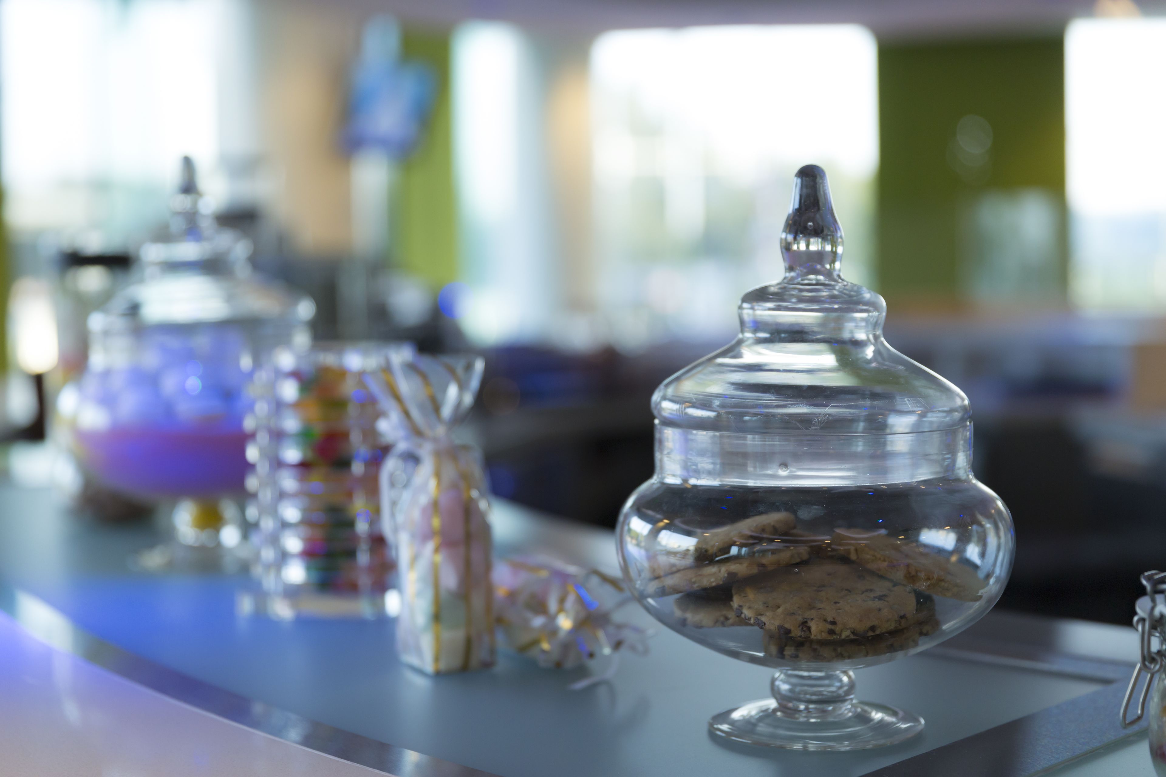 Un espace bar avec des récipients en verre transparent contenant des biscuits et un bocal décoratif en verre.