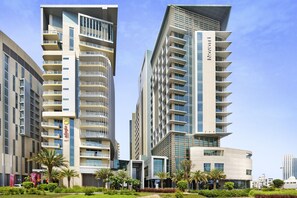 A modern hotel with multiple floors, balconies, and a well-maintained garden area.