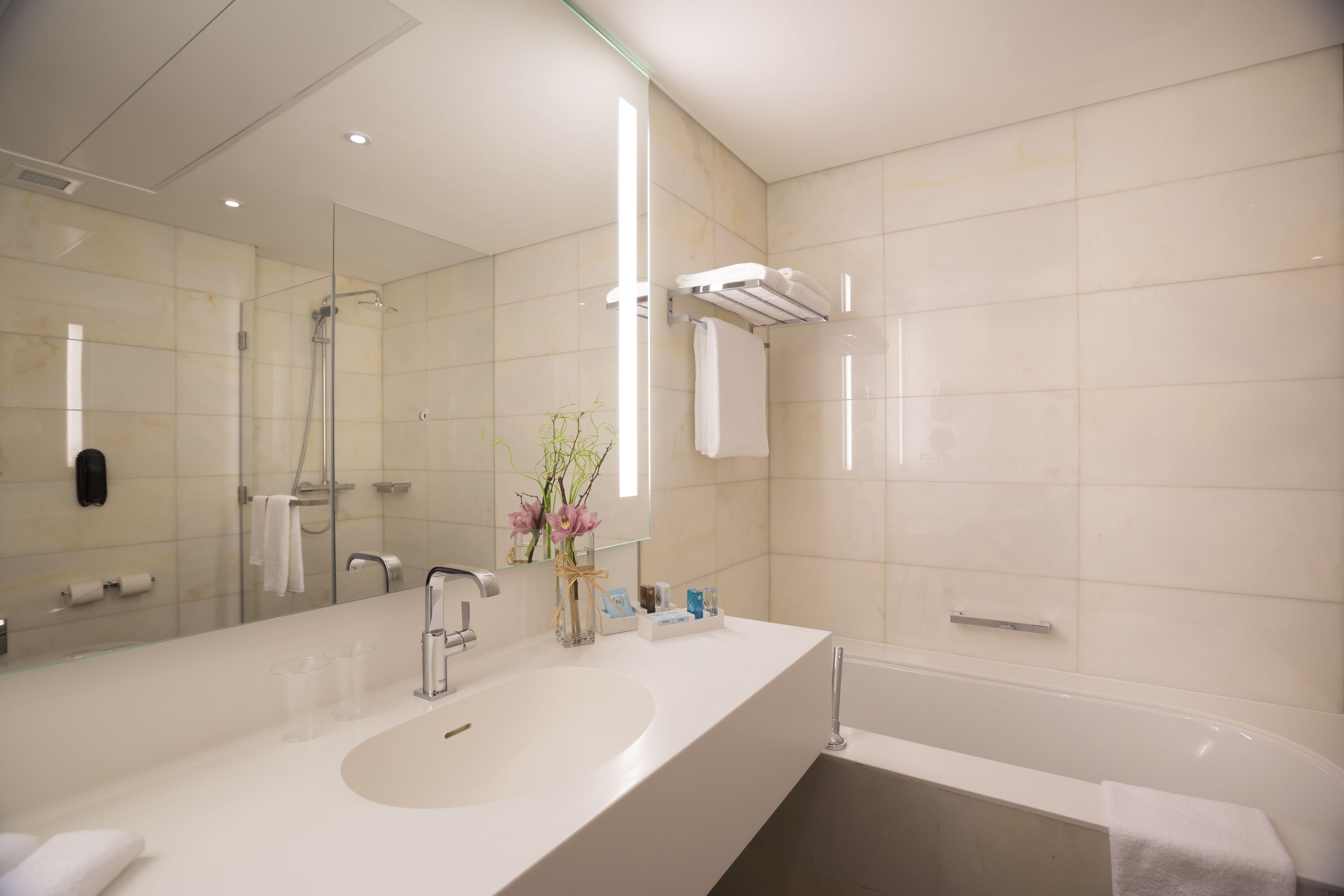 Une salle de bain moderne avec un grand miroir, un lavabo et une baignoire.