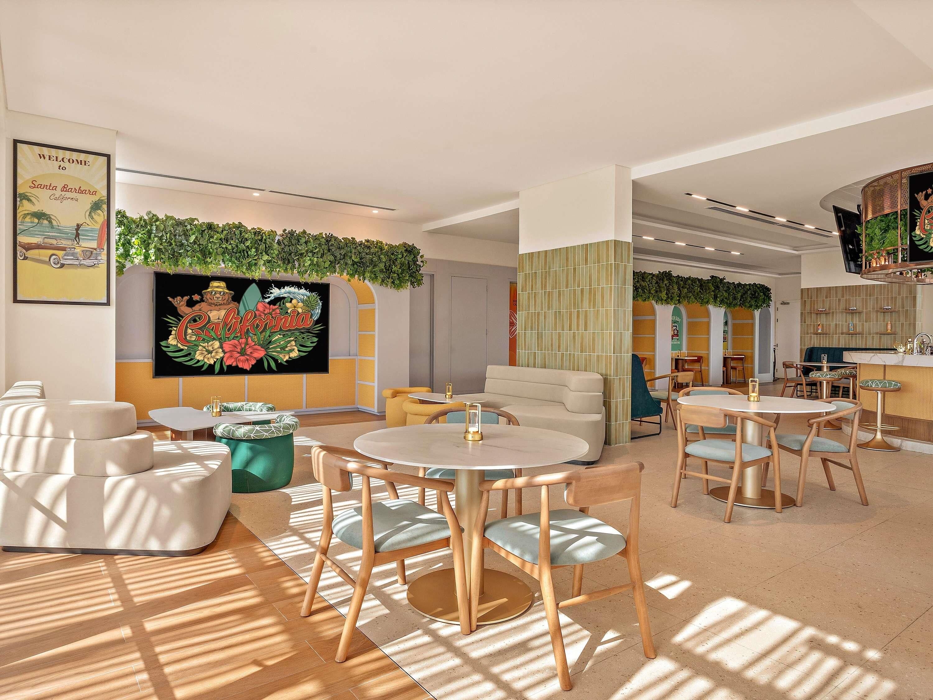 Un interior moderno con mesas y sillas redondas, una gran obra de arte floral y una zona de bar.