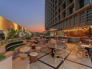 Un espace extérieur aménagé avec des tables et des chaises, un bar et un bâtiment doté de grandes fenêtres.