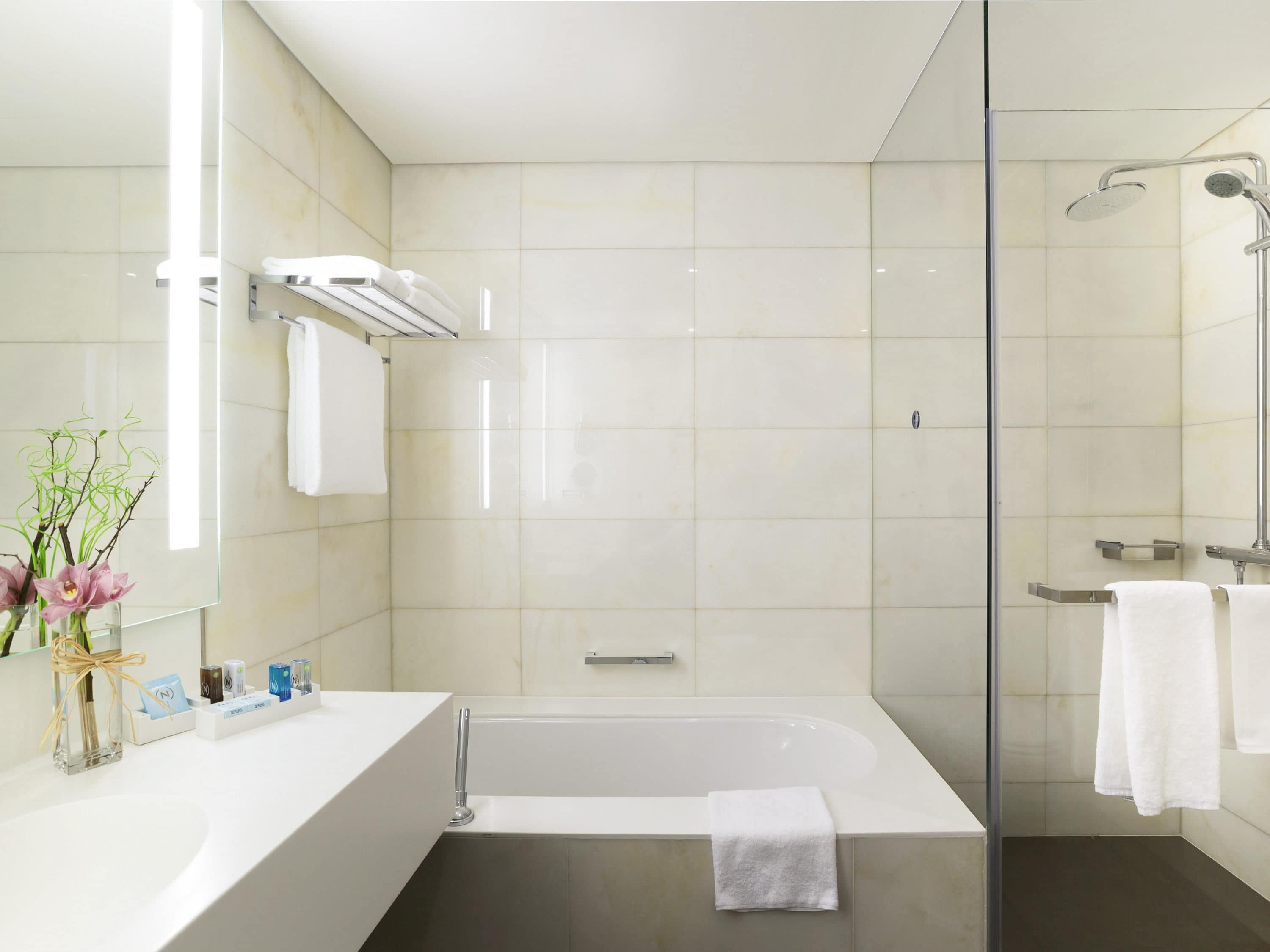 A modern bathroom with a bathtub, a glass shower enclosure, and a vanity with a mirror.