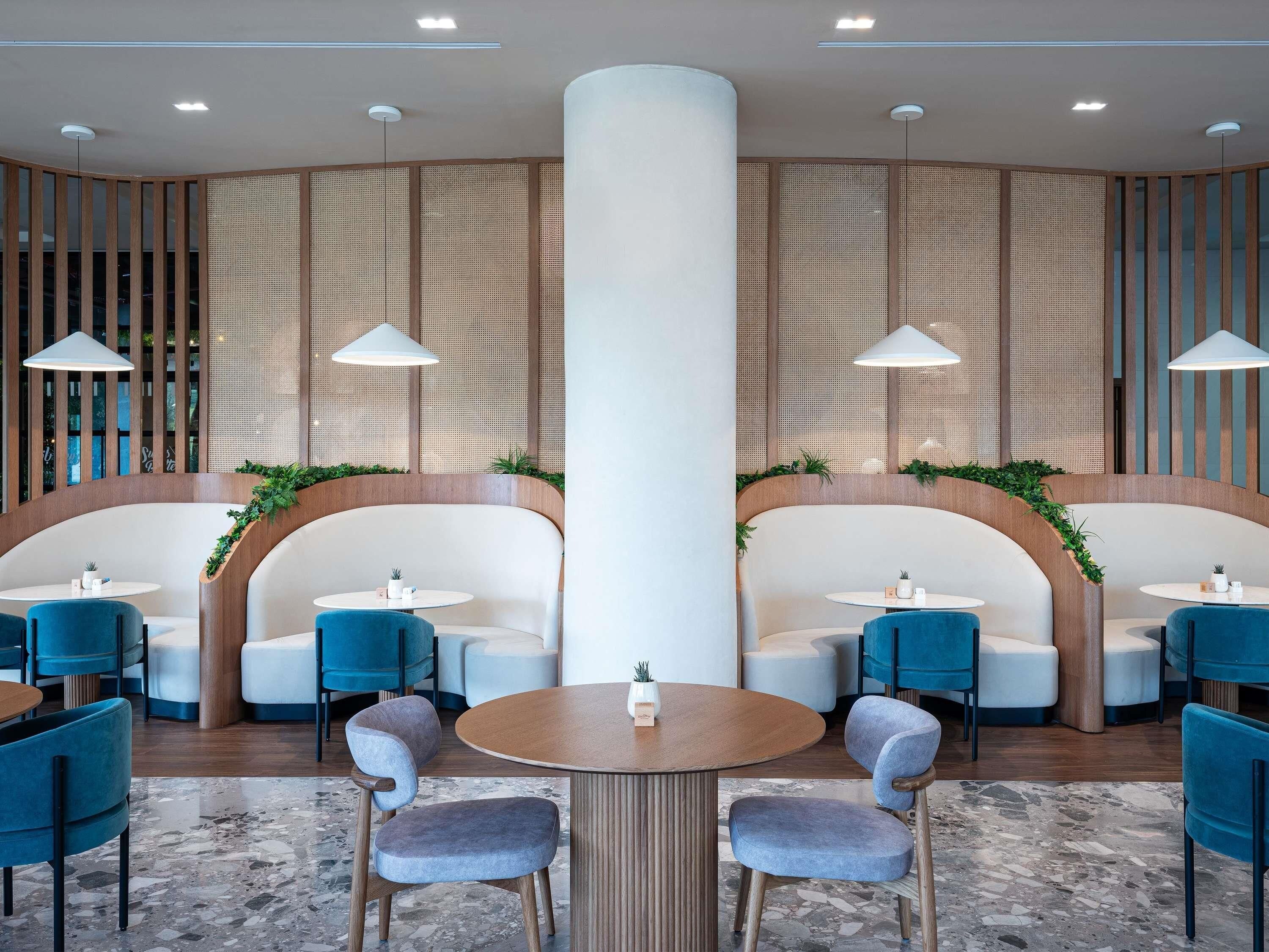 A modern interior with seating areas, round tables, and pendant lighting.