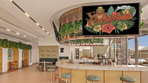 A bar area with a tropical-themed mural, a counter with stools, and a seating area with tables and chairs.