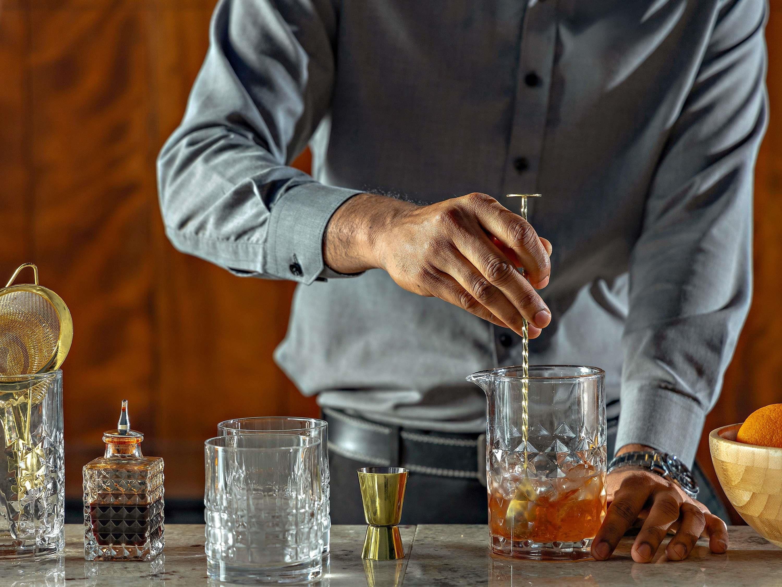 A bartender pouring a drink into a glass.