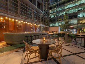 An indoor bar area with a bar counter, stools, and tables.