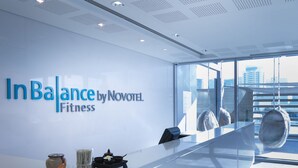 Een moderne fitnessruimte met een receptiebalie, een groot raam en een plafond met een uniek patroon.
