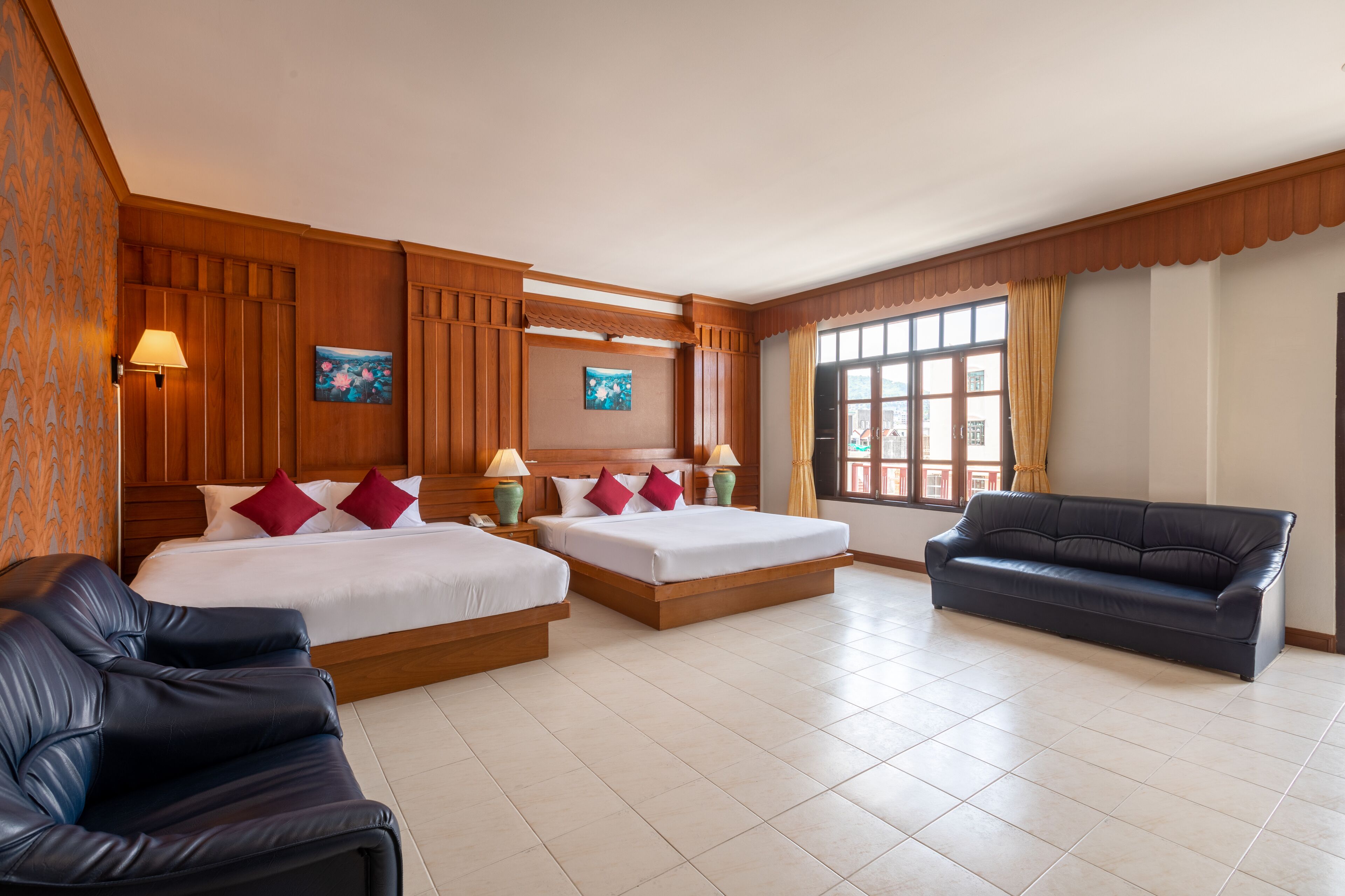 A hotel room with two beds, a sofa, and a large window.