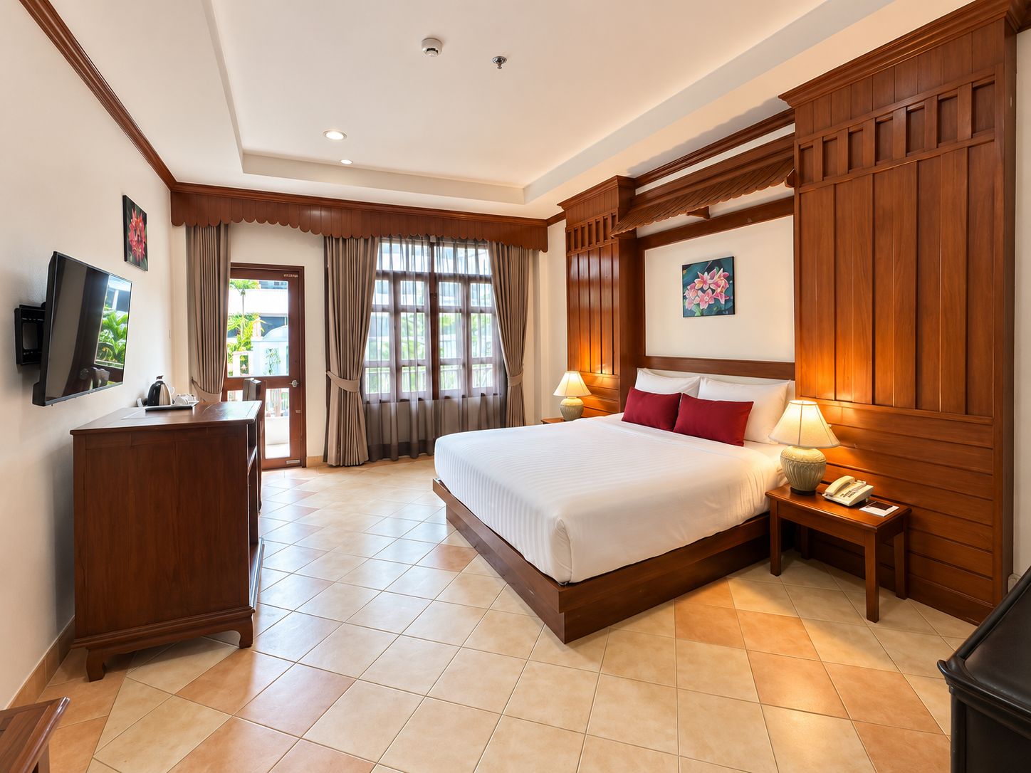 A hotel room with a large bed, bedside tables, a desk, a television, and a window with curtains.