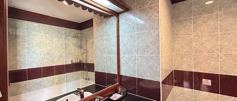 A bathroom with a sink, mirror, and shower.