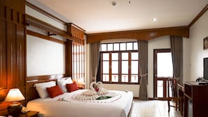 A hotel room with two beds, a television, a desk, and a large window with curtains. - Tony Resort (Patong)