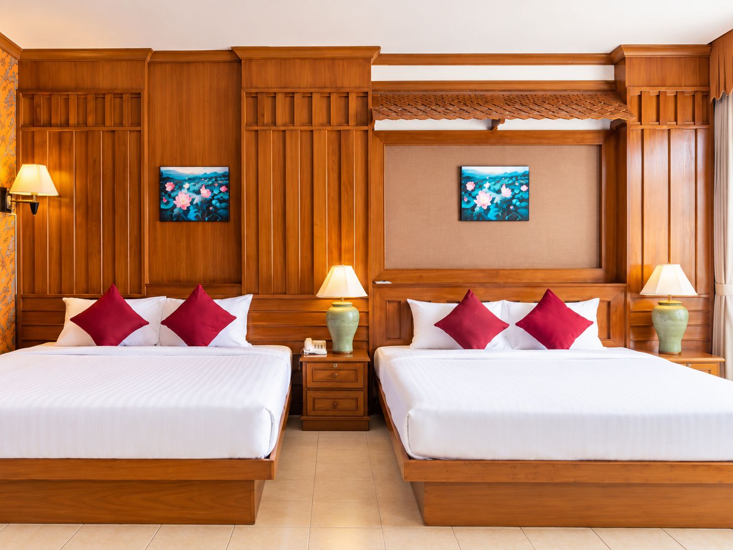 Quarto de hotel com duas camas, painéis de madeira, duas luminárias fixadas na parede e duas obras de arte emolduradas.