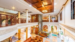 A spacious lobby with a marble floor, wooden furniture, and a high ceiling with chandeliers. - Tony Resort (Patong)