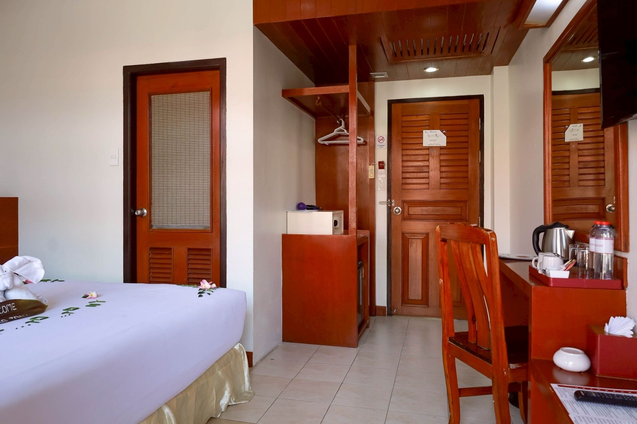 Una habitación de hotel con cama, escritorio con tetera, silla y armario de madera.