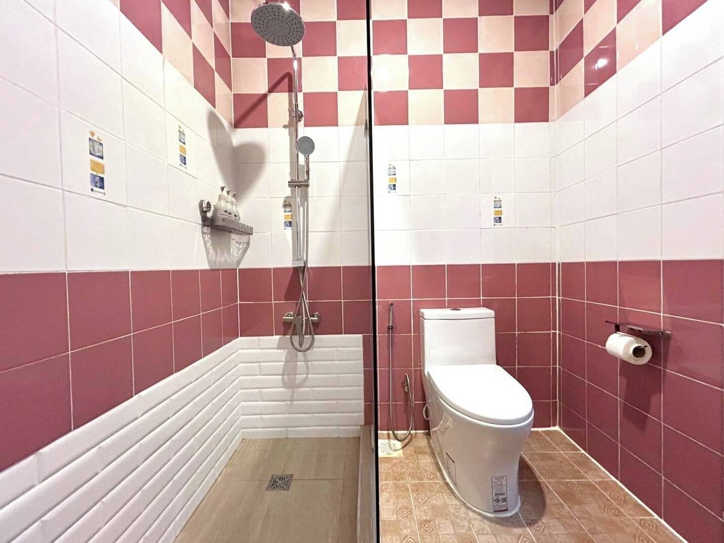 A bathroom with a shower, toilet, and tiled walls.