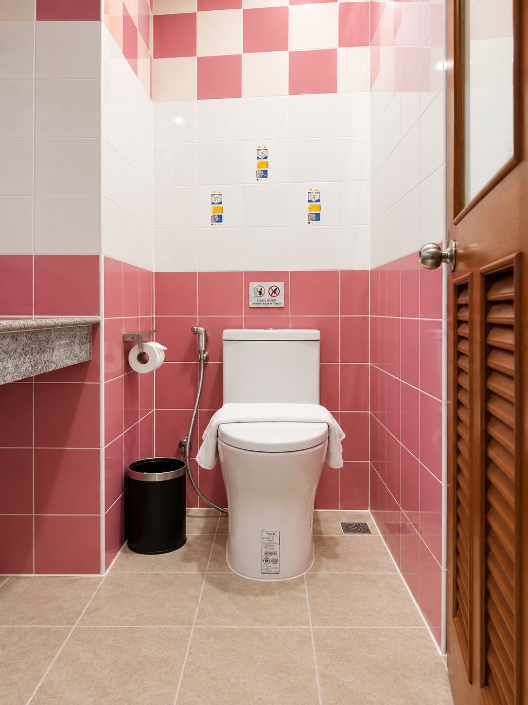 Une salle de bain équipée de toilettes, d’une poubelle, d’un porte-serviettes et d’une douche.