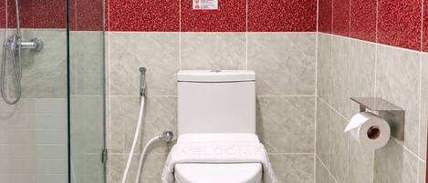 A bathroom with a toilet, shower, and glass-enclosed shower stall.
