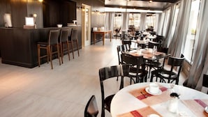 En modern restaurang med en bardel, flera matbord och stolar.
