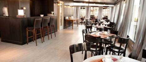 A modern restaurant with a bar area, multiple dining tables, and chairs.