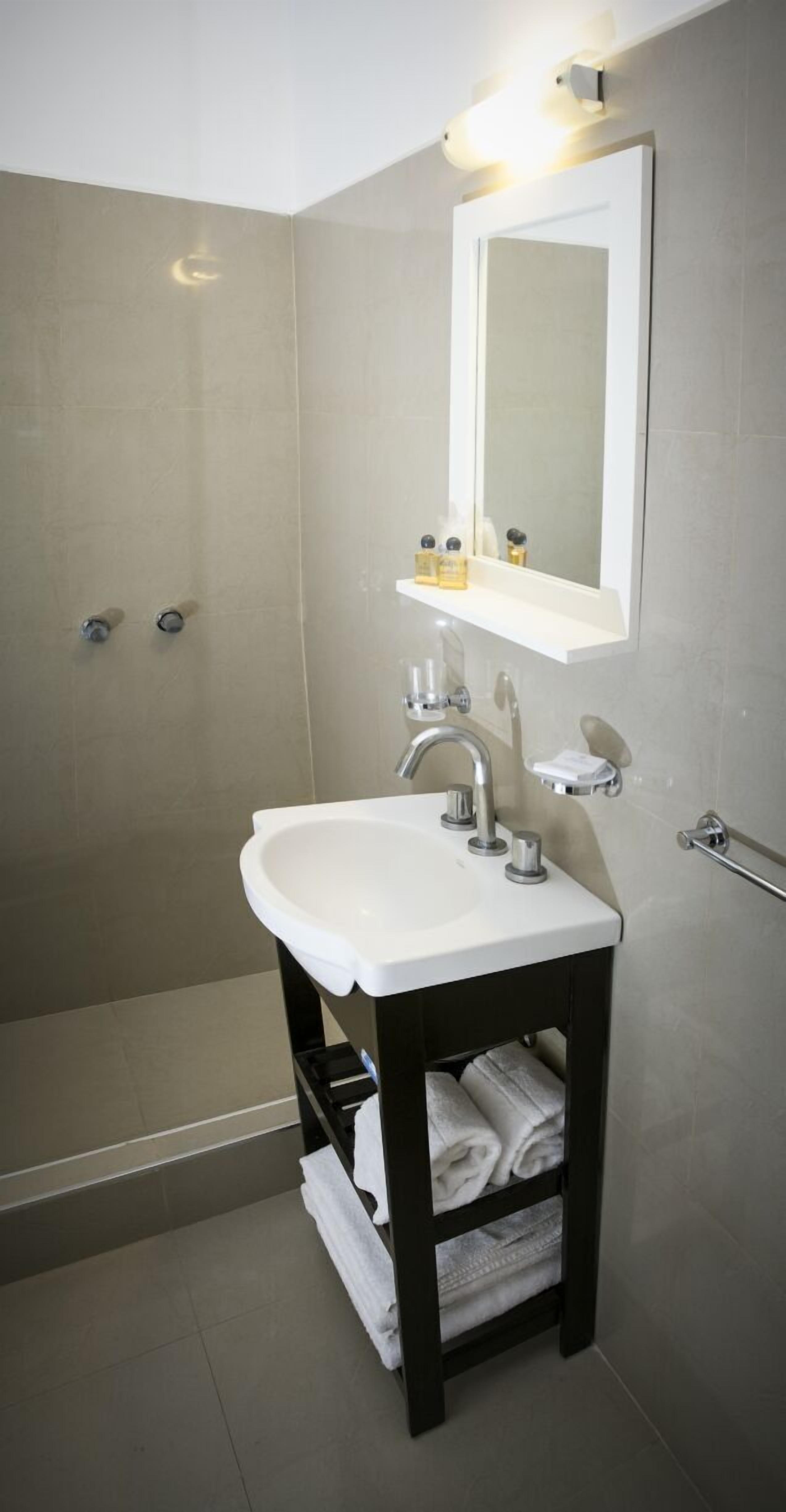 A modern bathroom with a white sink, a mirror, and a shower.
