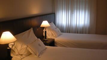 Una habitación de hotel con dos camas, cada una con una lámpara de noche y un teléfono en la mesita.
