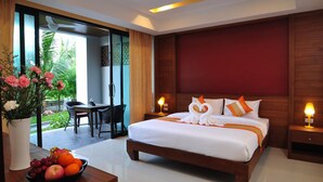 A hotel room with a large bed, a dining area, and a view of greenery outside. - Samui Honey Tara Villa Residence (Koh Samui)