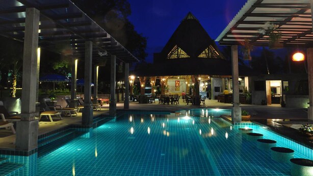 An outdoor swimming pool with lounge chairs and a covered seating area at dusk. - Samui Honey Tara Villa Residence (Koh Samui)