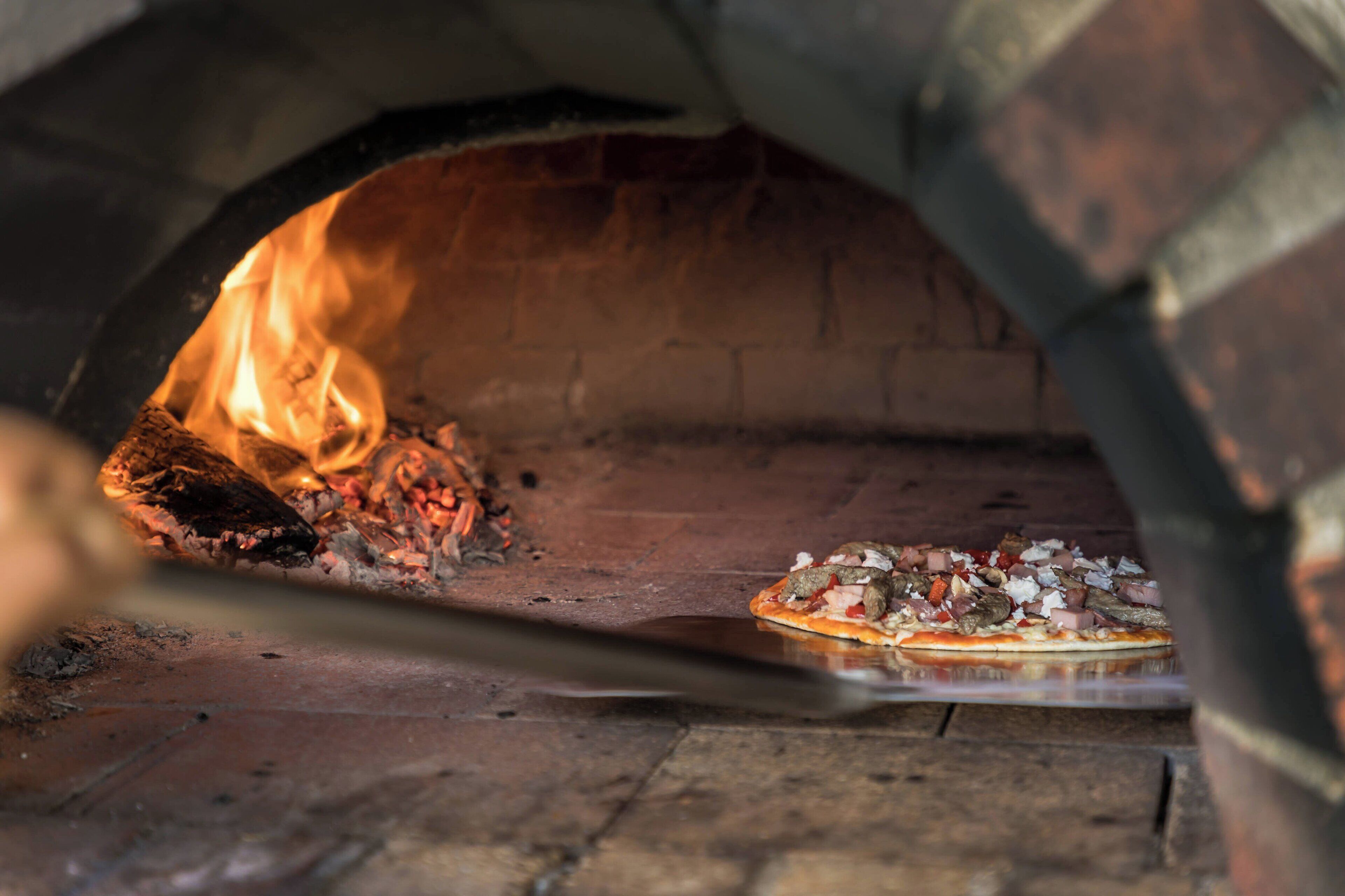 Une pizza est en train de cuire dans un four en briques.
