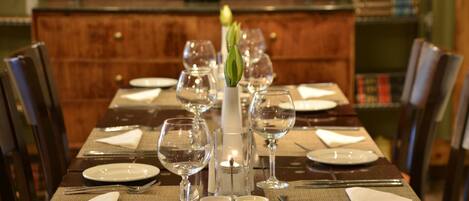 Una mesa de comedor preparada para una comida, con platos, cubiertos y copas de vino.