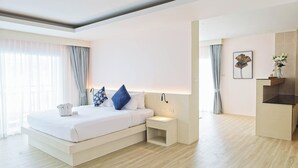 A modern hotel room with a bed, bedside table, and a small desk area. - Amata Patong (Patong)