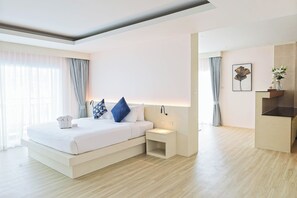 A modern hotel room with a bed, bedside table, and a small desk area. - Amata Patong (Patong)