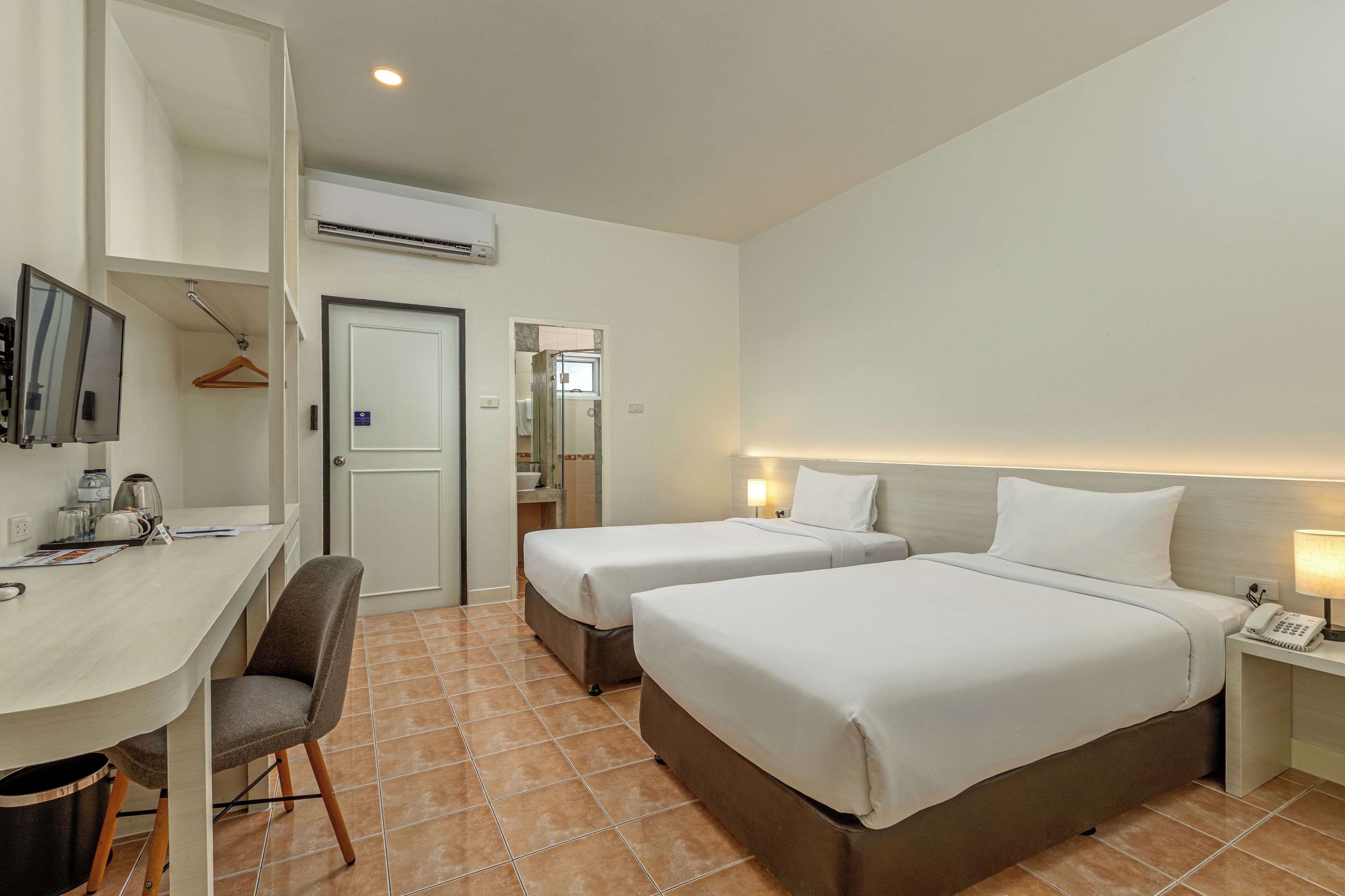 Une chambre d’hôtel avec deux lits, un bureau, une chaise, une télévision et une salle de bain avec douche.