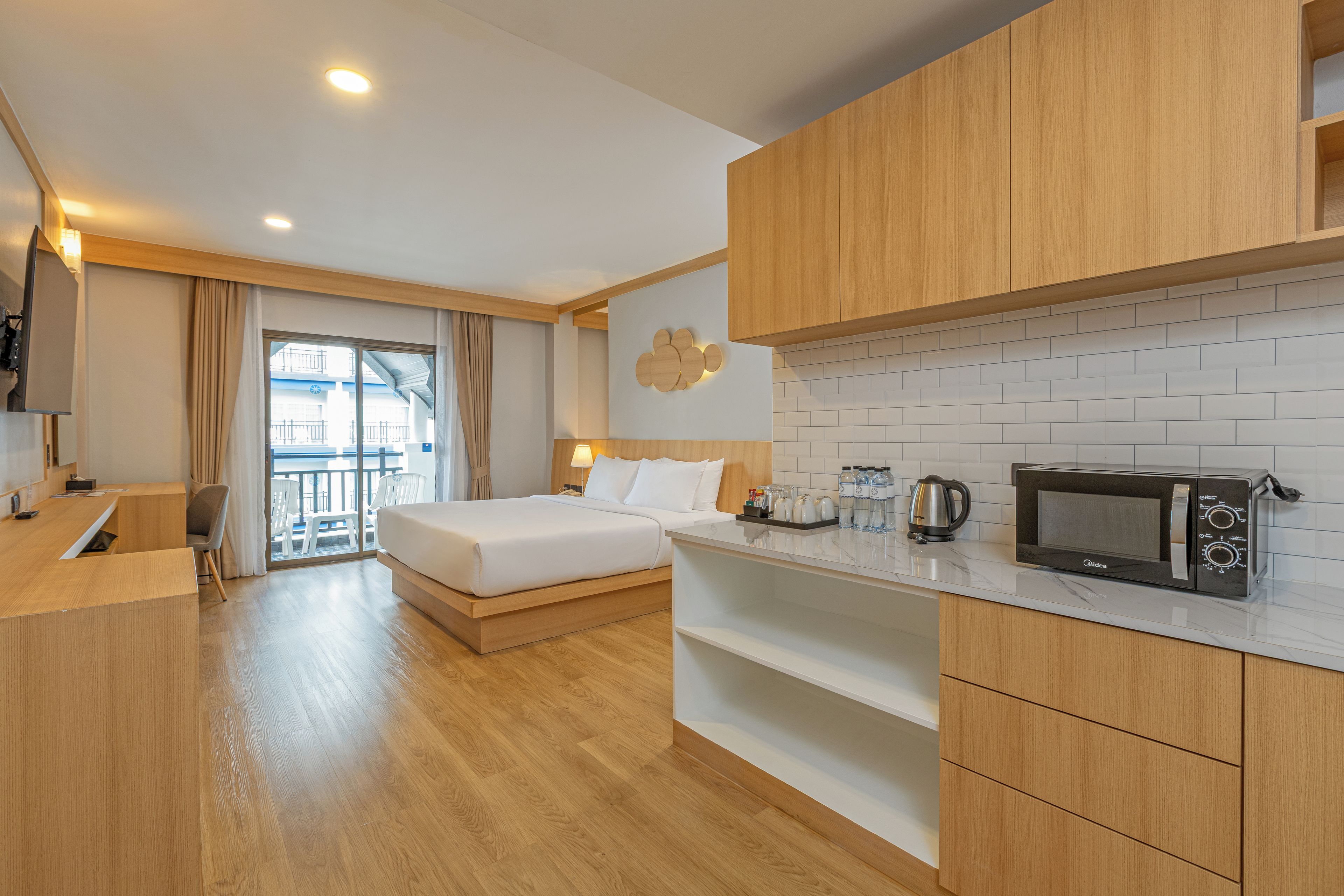 Quarto de hotel com cama, escrivaninha, cozinha compacta e vista para o exterior.