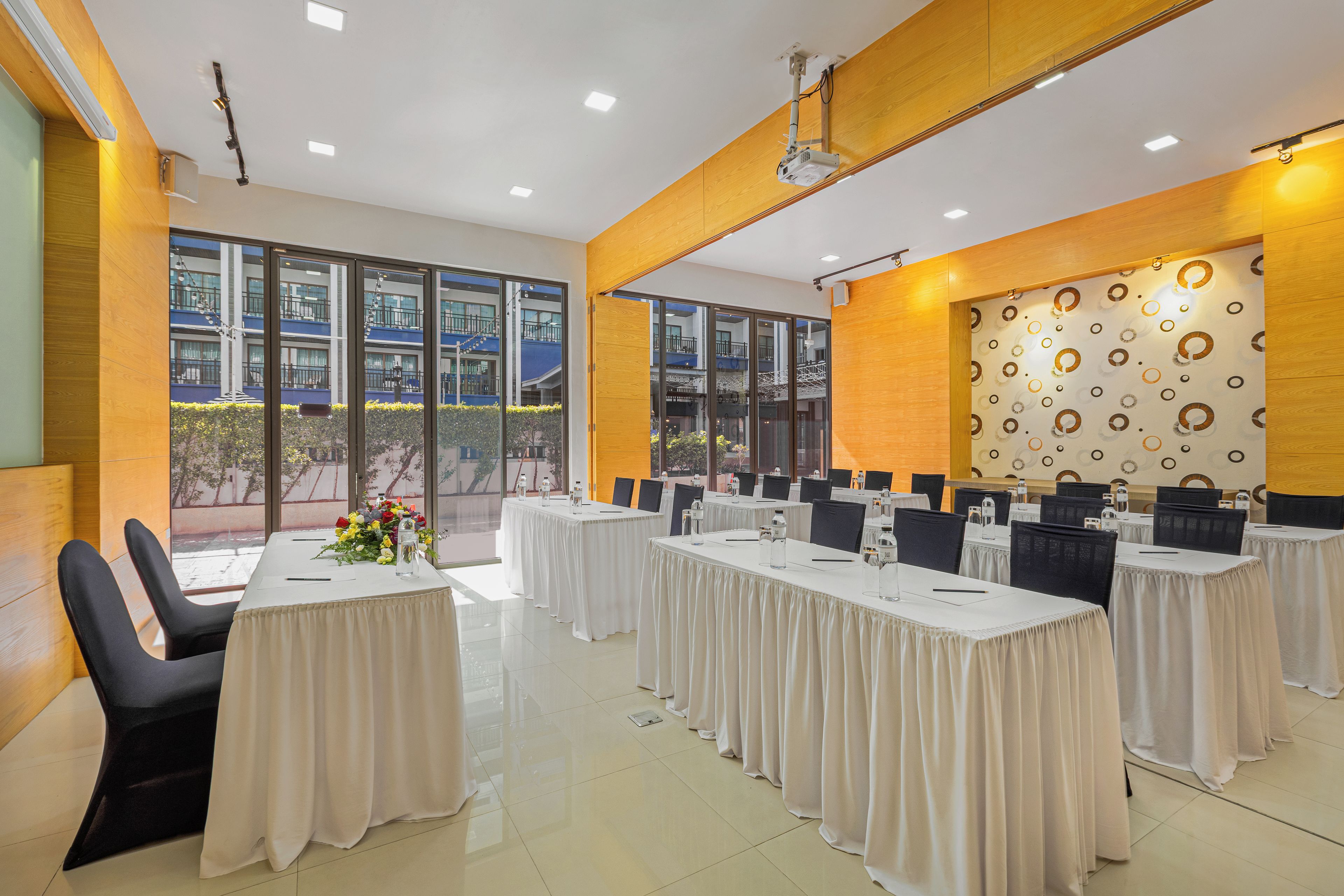 A conference room with multiple tables, chairs, and a large window with a view of buildings.