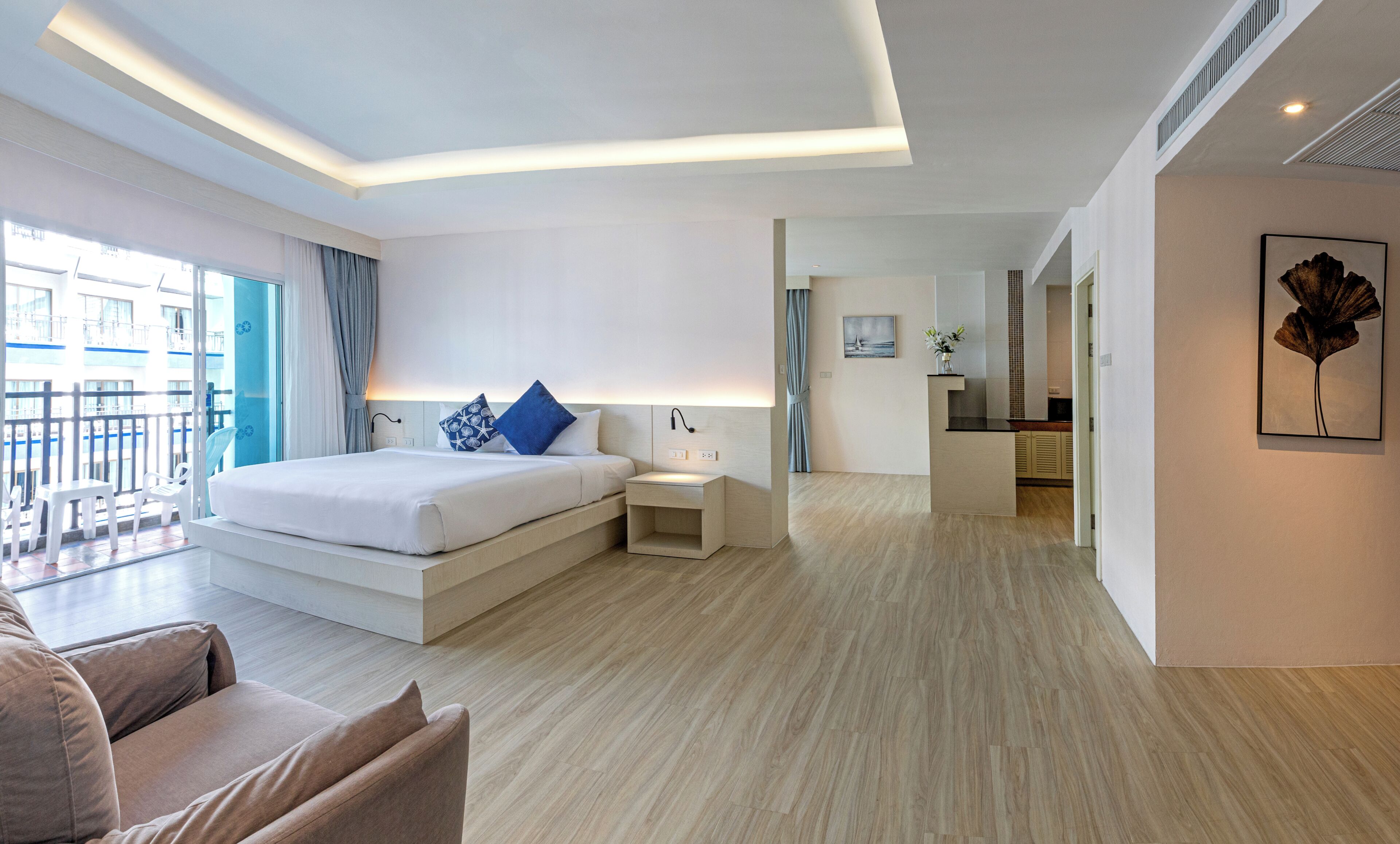 A modern hotel room with a large bed, bedside table, and a view of the balcony.