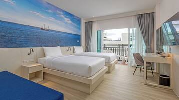 A hotel room with two beds, a desk, a chair, a balcony with a view of the sea, and a mural of the sea.