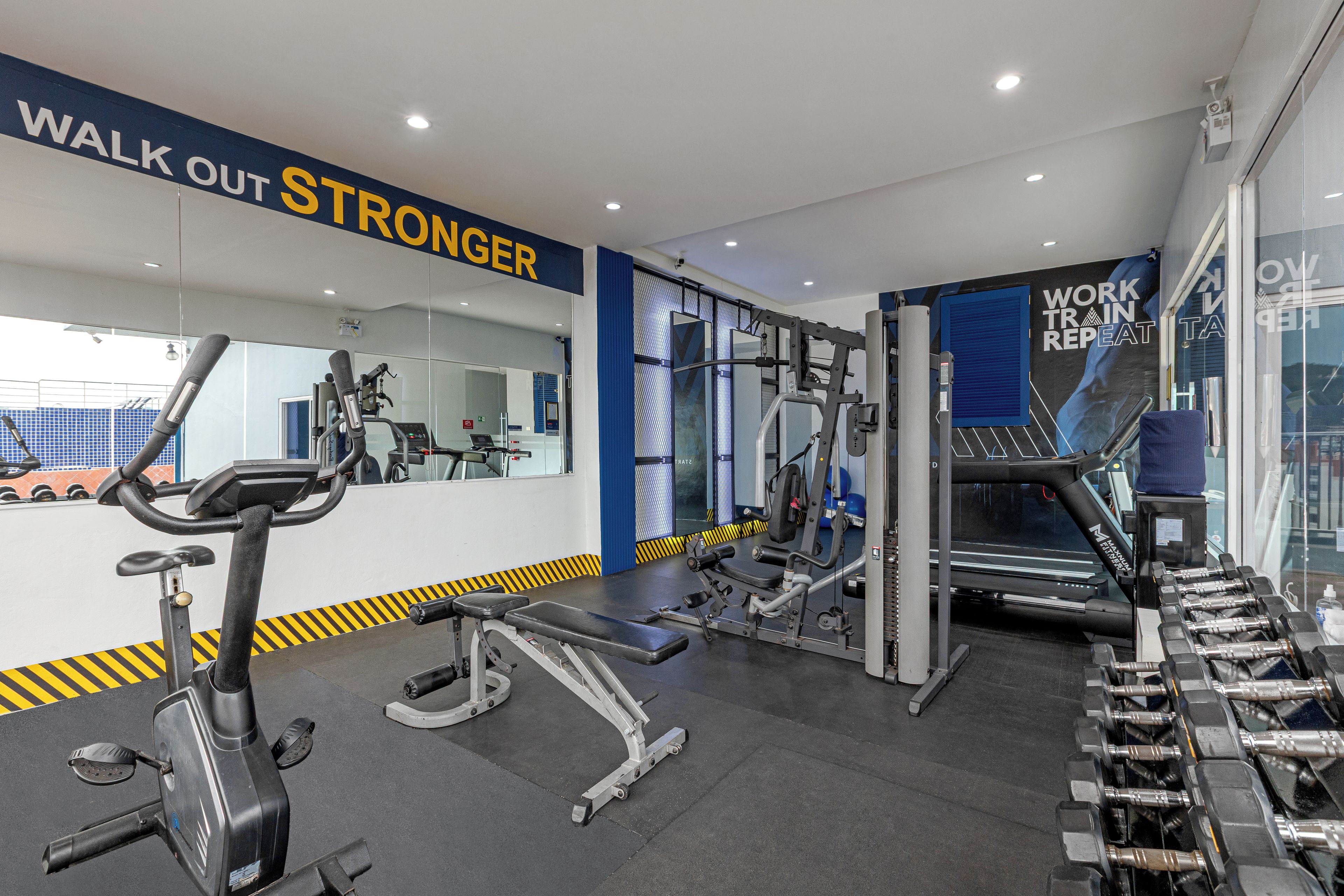 A gym with exercise equipment, a treadmill, and a wall with motivational text.