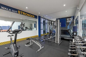 Une salle de sport équipée de matériel d’exercice, d’un tapis de course et d’un mur orné de messages motivants.