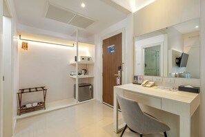 A hotel room with a desk, chair, and a mirror. There is a shelf with a kettle and a coffee machine. - Amata Patong (Patong)