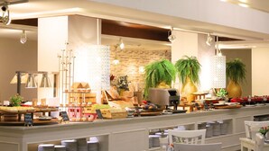 A buffet setup with various food items and a seating area with white chairs and tables. - Amata Patong (Patong)
